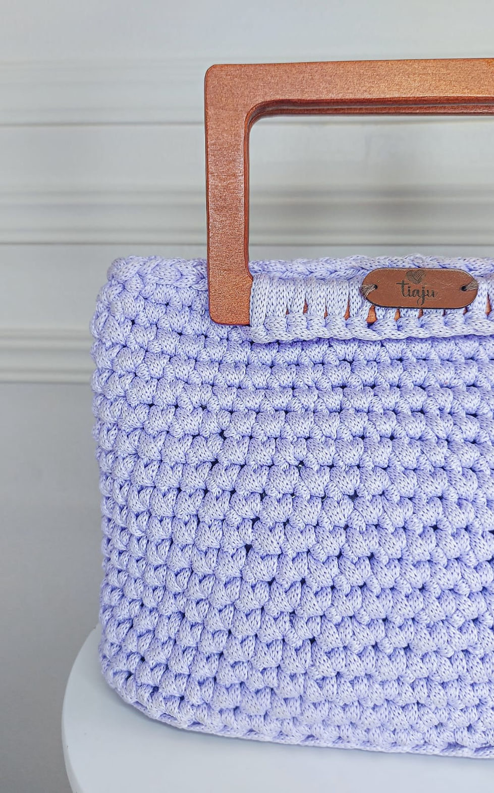 Bolsa em crochê com fio de malha na cor lilás, alça retangular em madeira tratada.