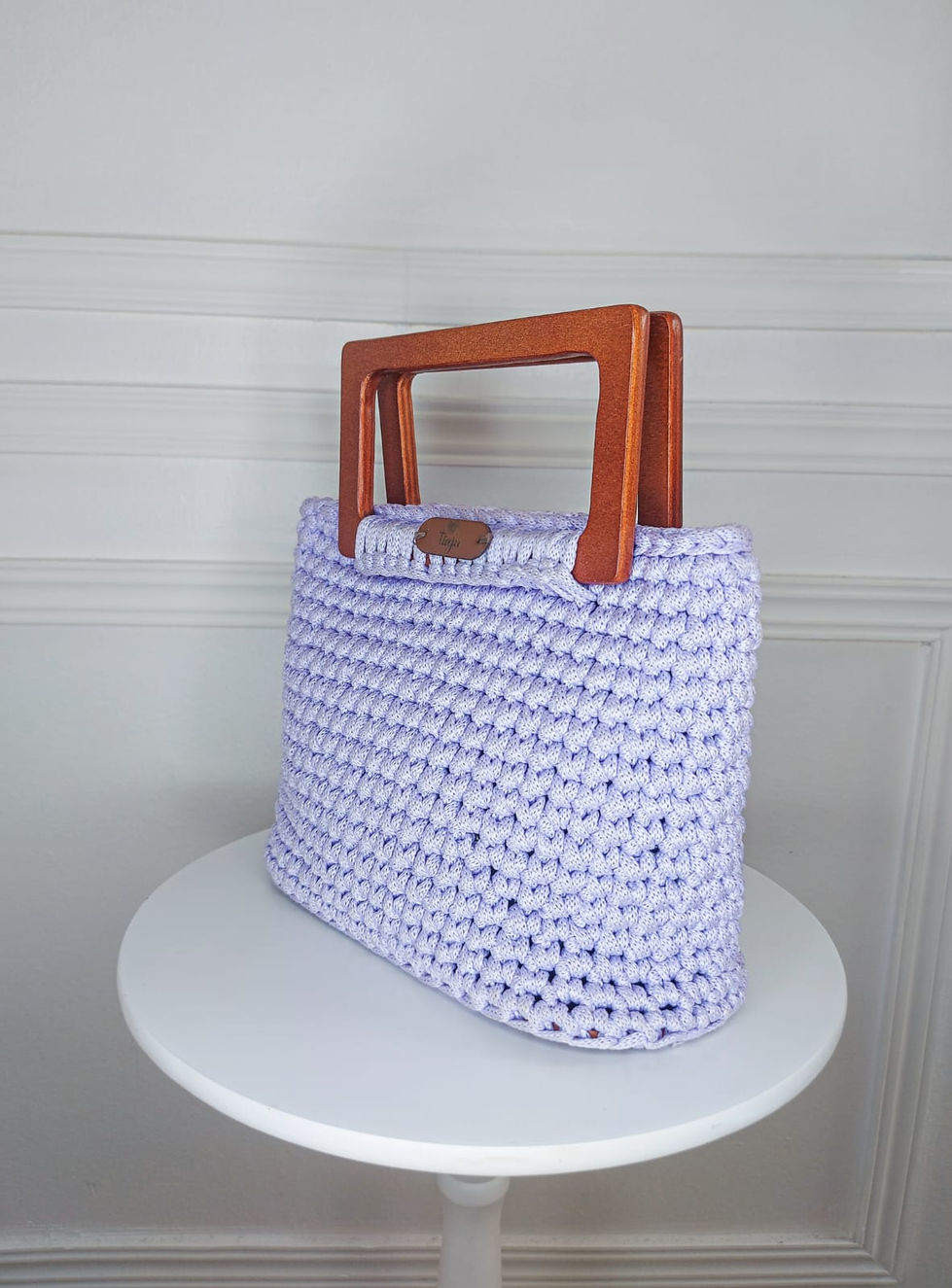 Bolsa em crochê com fio de malha na cor lilás, alça retangular em madeira tratada.
