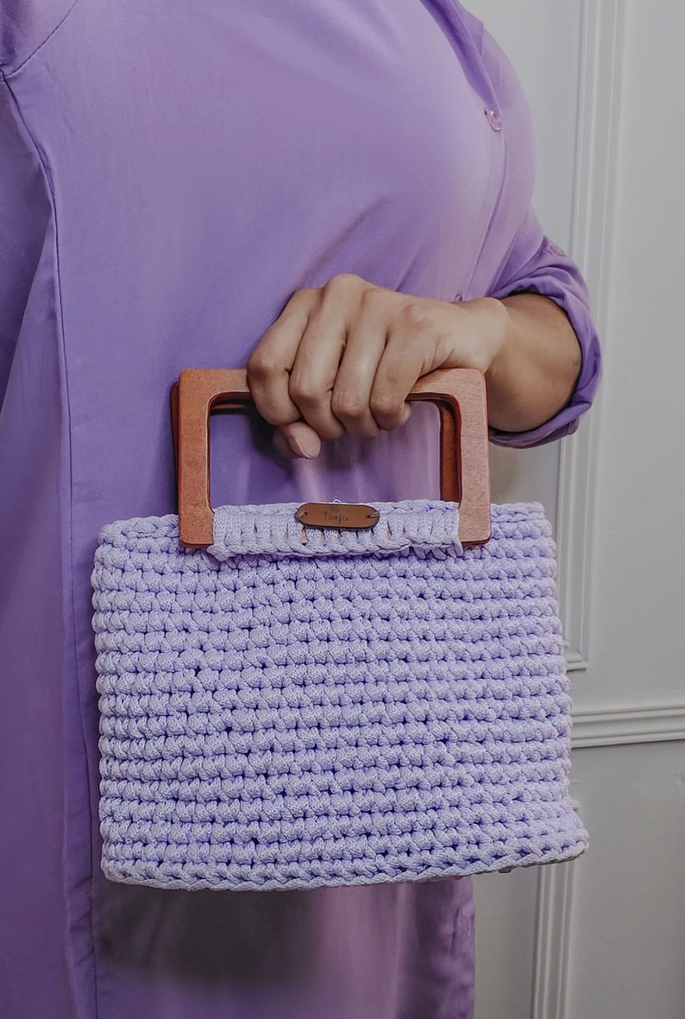 Bolsa em crochê com fio de malha na cor lilás, alça retangular em madeira tratada.
