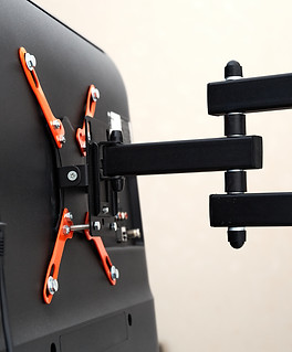 Swivel TV bracket LED display. Back view. X-shaped red fasteners. Black color. Multiplanar