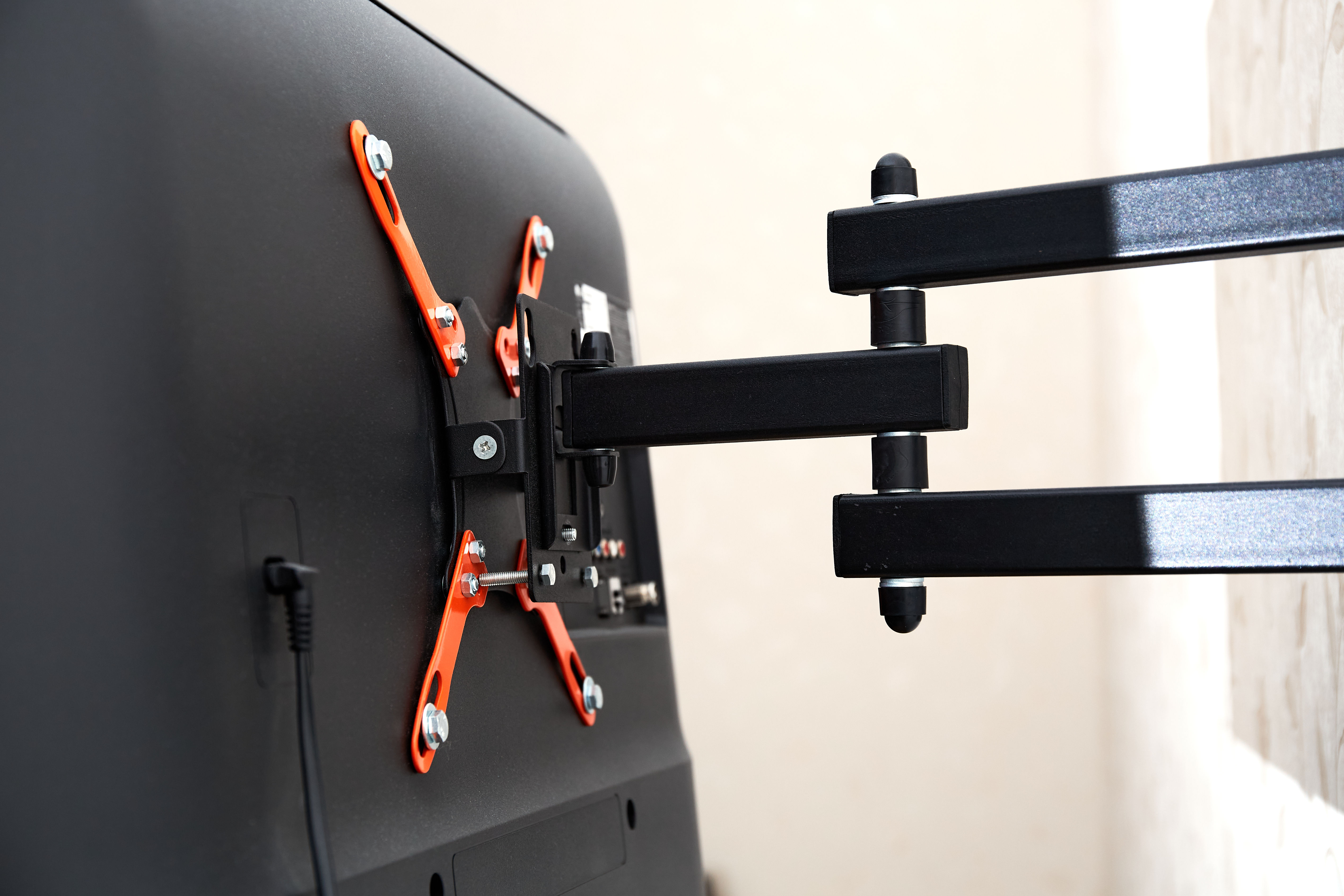 Swivel TV bracket LED display. Back view. X-shaped red fasteners. Black color. Multiplanar. Hangs on a wall. Reliable and comfortable fasten.