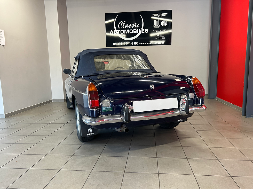 MG B coupé bleu foncé, vue arrière, exposée dans l’atelier Classic Automobiles.