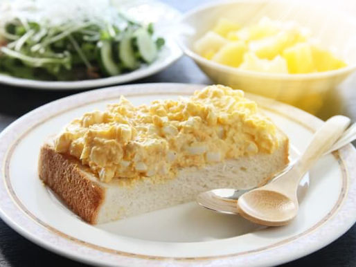 snee wit brood met eiersalade een metalen en houten lepel