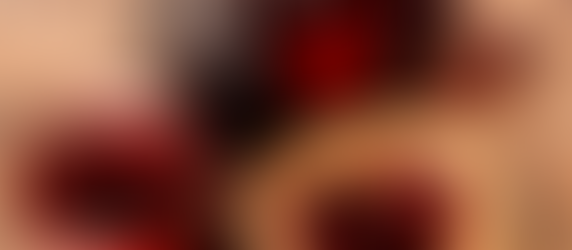 Twee potjes rode jam en een boterham met een jamhartje op houten tafel. Gedroogde bessen verspreid eromheen. Warm en huiselijk.