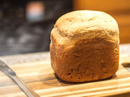 Vers gebakken goudbruin tarwebrood uit een broodbakmachine, met een knapperige korst en warme, zachte binnenkant.