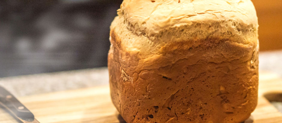 Vers gebakken goudbruin tarwebrood uit een broodbakmachine, met een knapperige korst en warme, zachte binnenkant.
