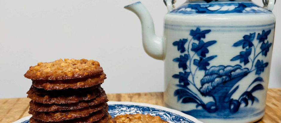 kletskoppen platte bruine koekjes op bord naast theepot