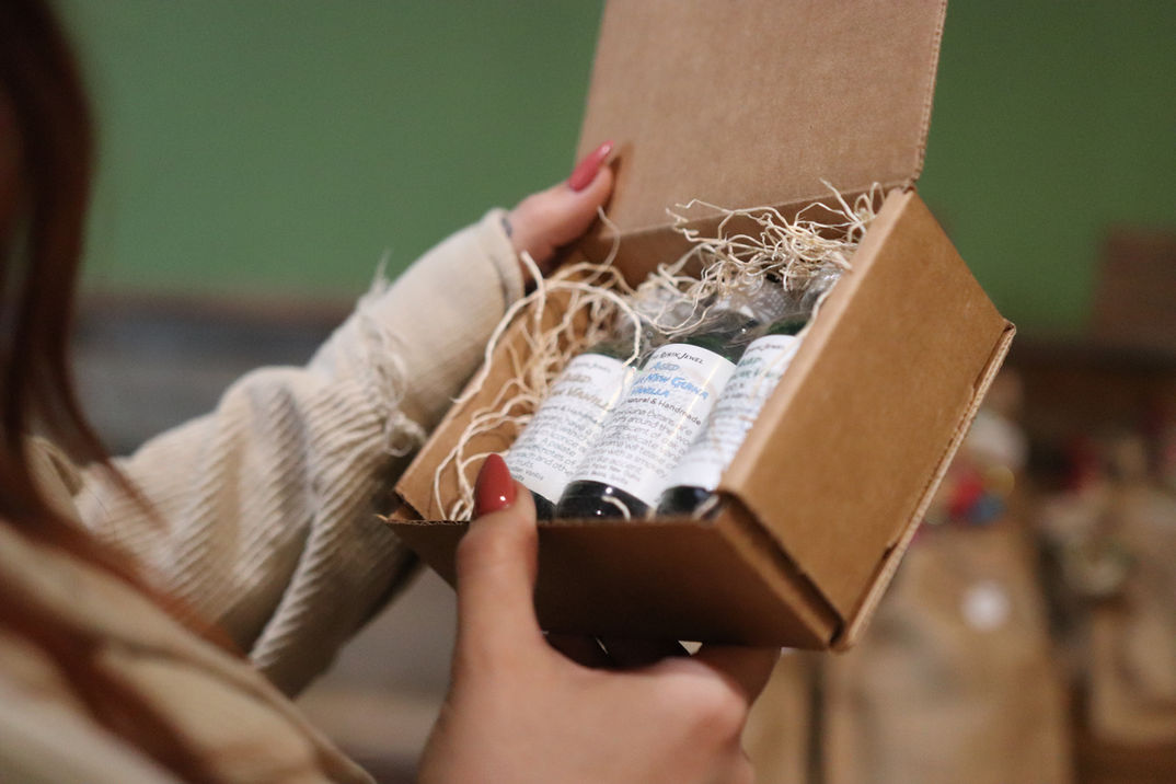 A woman holds a box filled with bottles of organic all-natural essential oils.