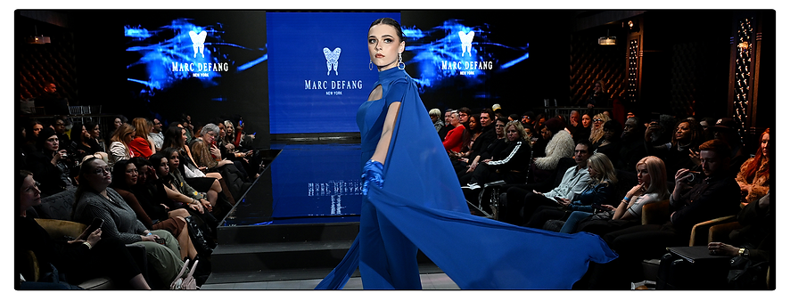 A model in a blue designer gown walks the fashion runway for designer Marc Defang.