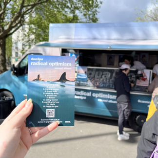 A flyer for Dua Lipa's album, in front of a food truck with the same theme.