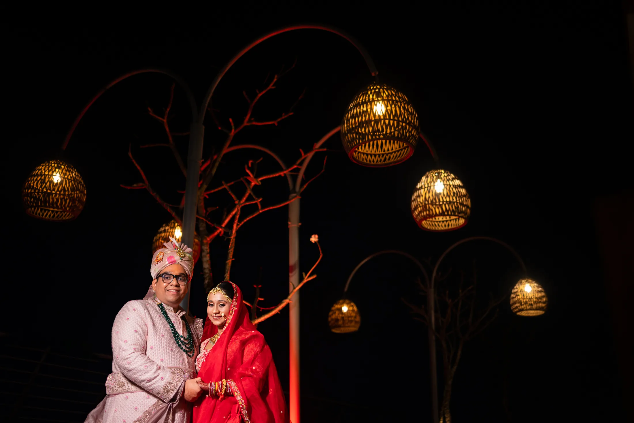 Couple beneath hanging lamps at night