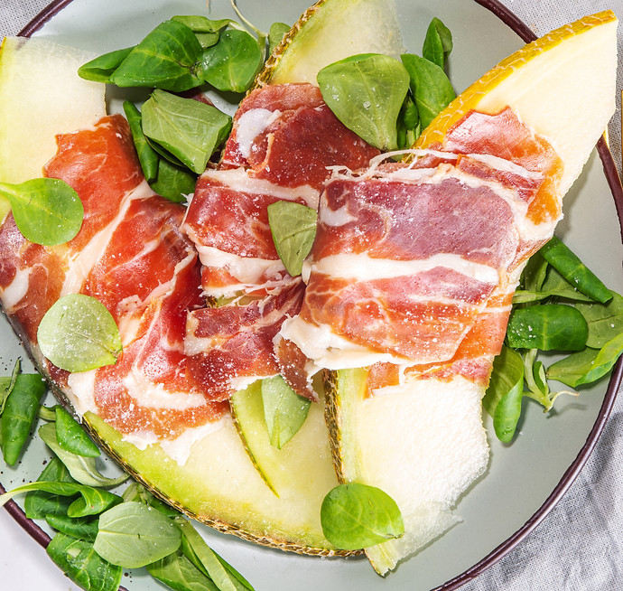 Fresh melon salad with prosciutto hamon and green leaves mix, autumn fruit vegetable salad