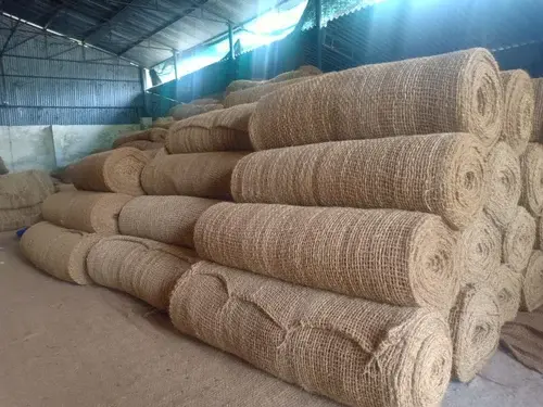 Rolls of coir geotextiles stacked in a storage facility, ready for use in erosion control and land management projects.