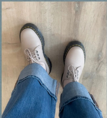 Sustainable Fashion portfolio: A first-person perspective of Michelle Marie Sawtell showcasing footwear textures, featuring taupe Dr. Martens leather boots with classic yellow stitching paired with wide-cuffed blue denim jeans.