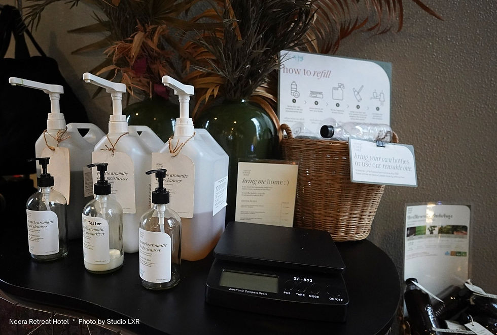 Bottles of aromatic cleanser and moisturizer with a digital scale on a table. Wicker basket and refill instructions in the background.