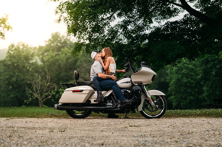 Newly engaged couple kissing on motorcycle during engagment portrait session.