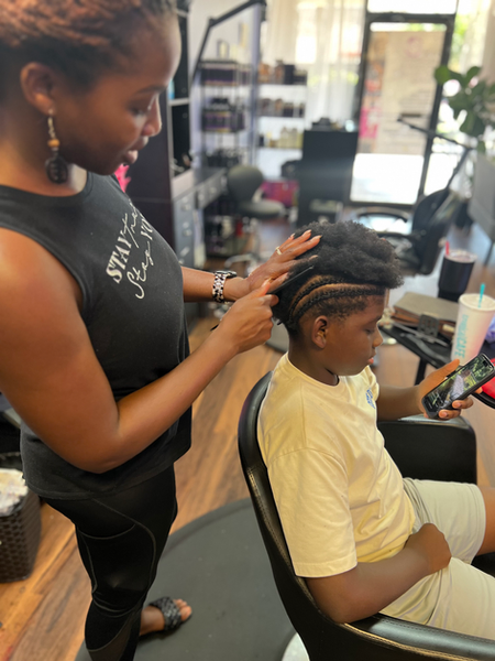 brown mannequin head with red lips and braids and unfocused background