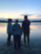 Silhuets of young people overlooking lake sunset