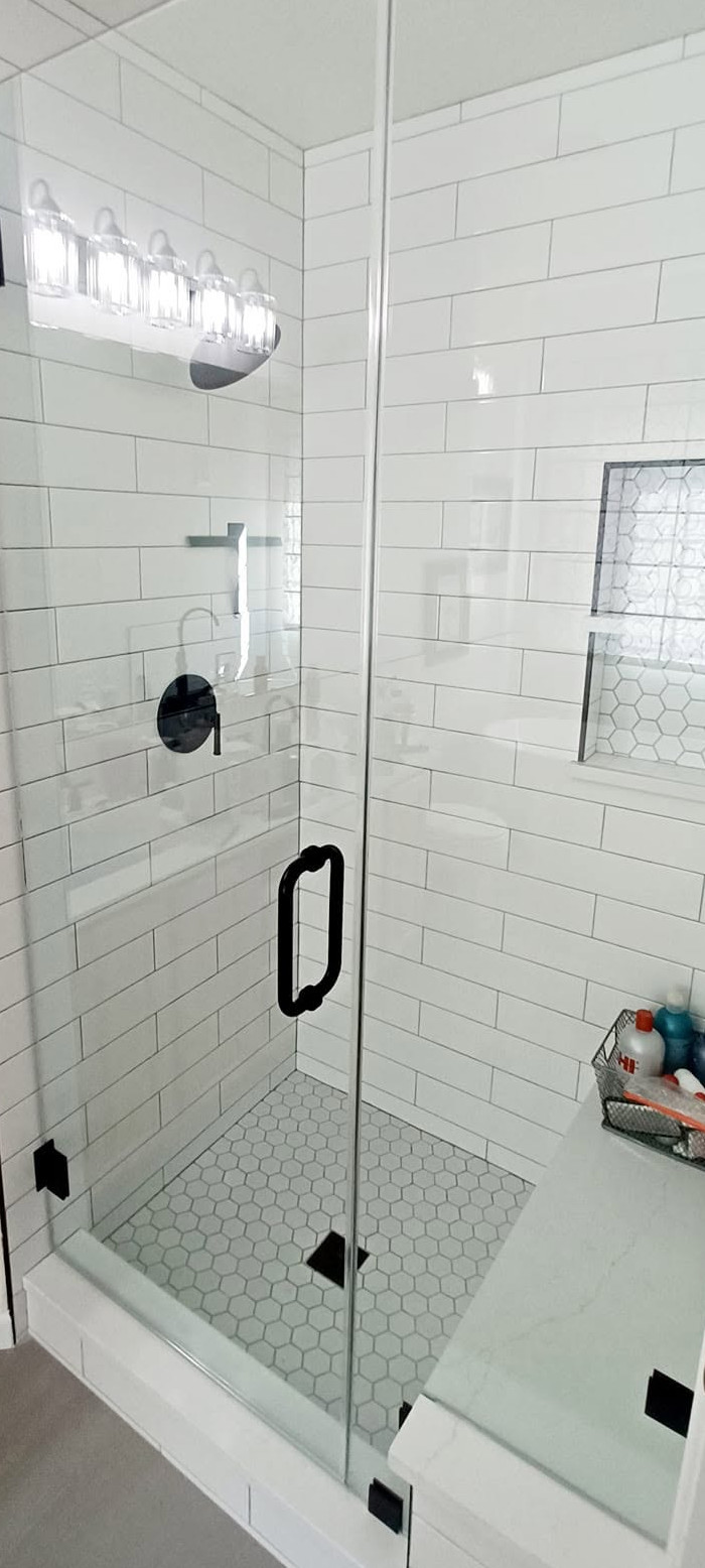 Modern shower remodel with glass doors and white subway tile.