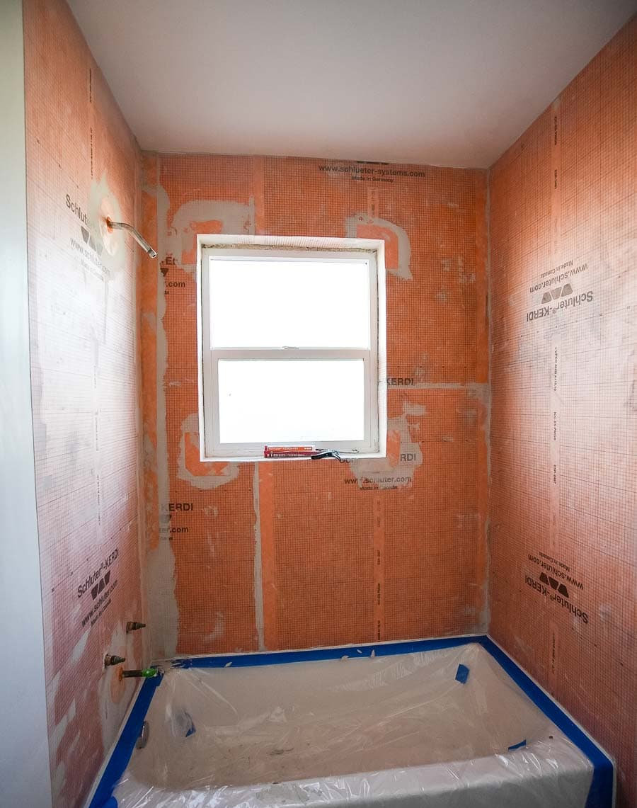 Close-up view of tiled bathroom wall showing waterproofing layers