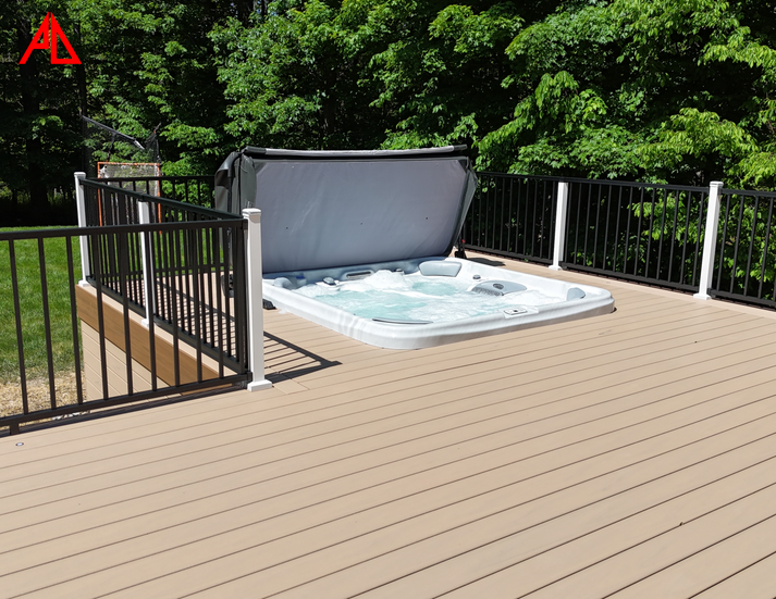 A composite deck Trex Carmel with a hot tub, surrounded by nature and featuring black and white railings.