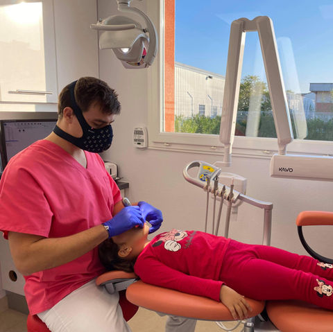 Une enfant sur le fauteuil tandis que le dentiste soigne une carie