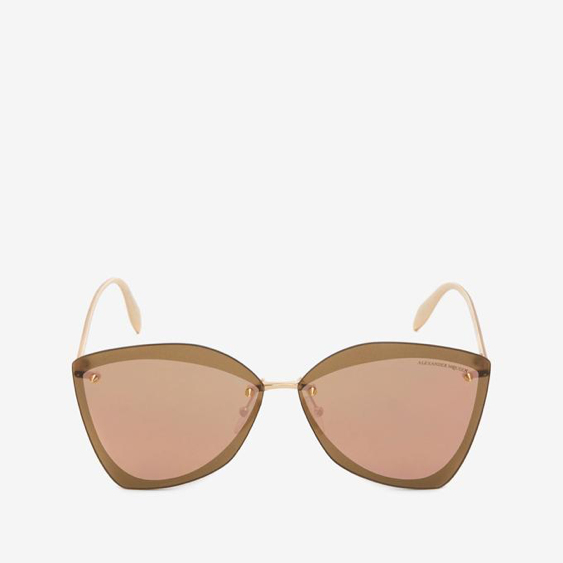 Modern shaped sunglasses with salmon colored lenses on a white background