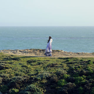 A woman standing on a cliff with the ocean in the background