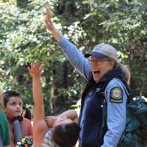 A State Parks Docent raising her hand with a group of kids