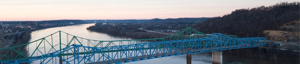 Blue truss bridge over river with town