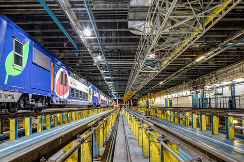 Atelier ferroviaire avec rame colorée en intervention.
