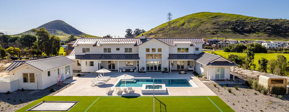 A new home with pool and tennis lawn with the green hill of San Luis Obispo in the background.