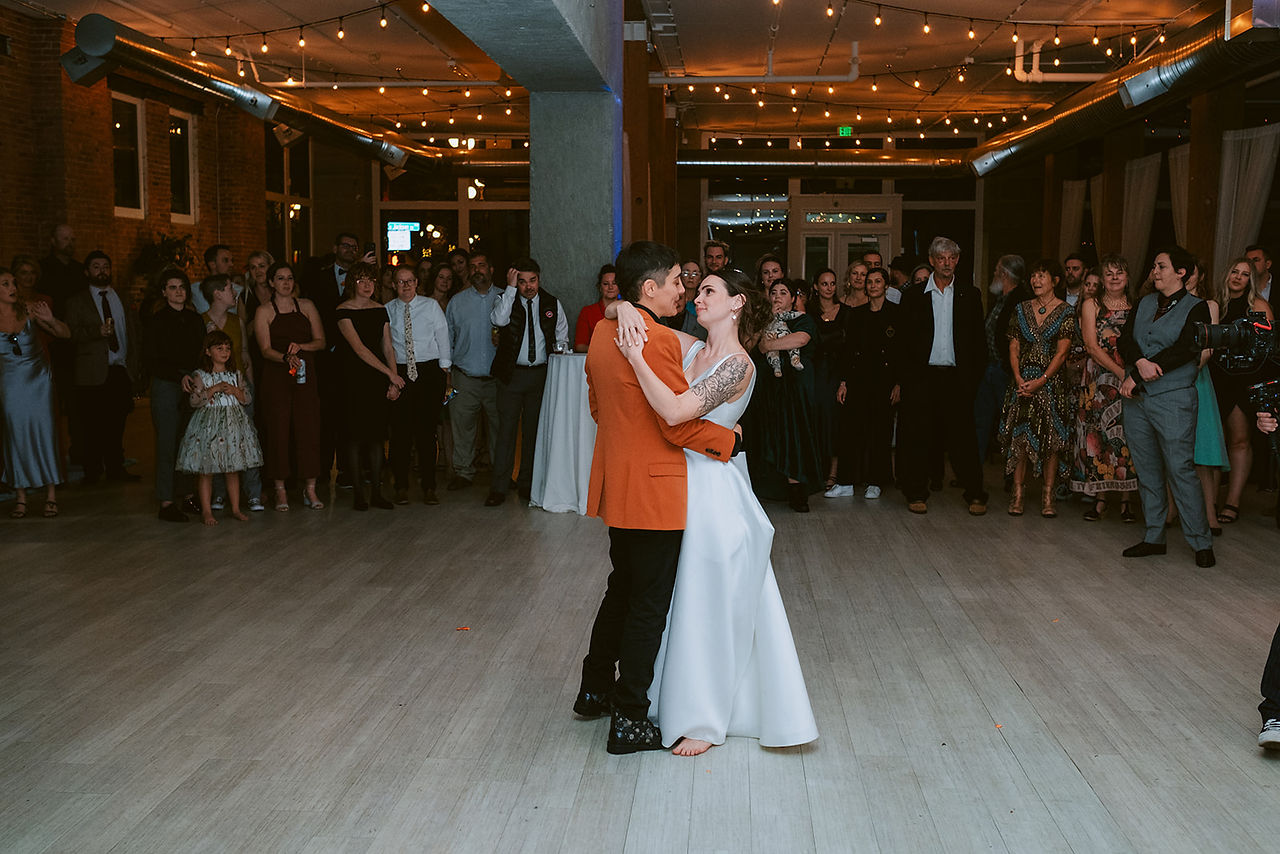 first dance with queer couple in orange suite and white dress