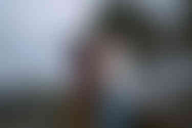 queer couple celebrating on beach in Seattle with ocean and driftwood behind, rocky beach, raining