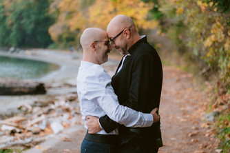 grooms holding each other closely on the beach