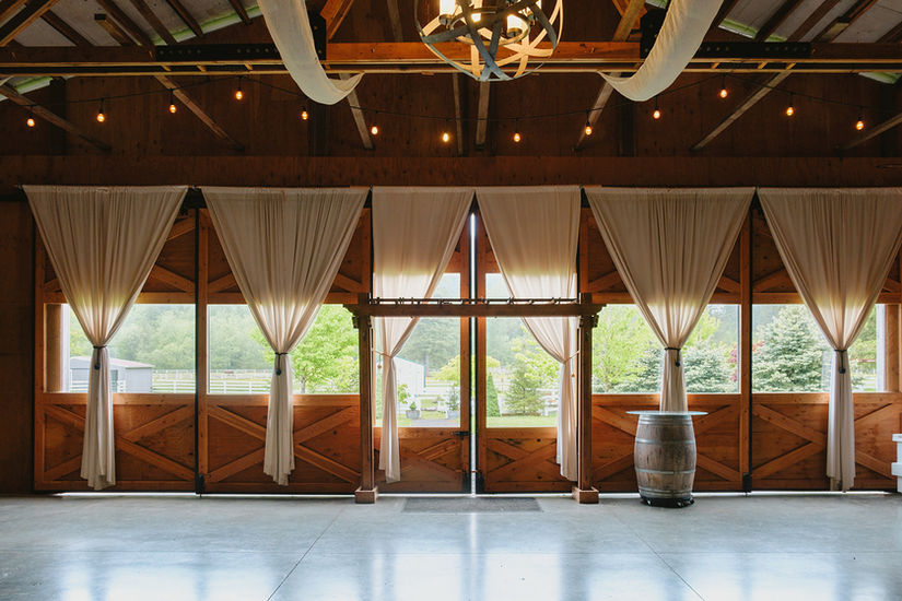 indoor barn space with white curtains and large windows