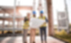 Three construction professionals in hard hats and safety vests reviewing architectural blueprints on a building site, illustrating the principle that Total Quality Management (TQM) requires deliberate planning, cross-functional collaboration, and a solid management foundation before improvement methods like Lean and Six Sigma can deliver lasting results.