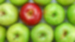 A top-down view of a neatly arranged grid of many green apples, with one single, distinct red apple positioned within the central-right area of the composition.
