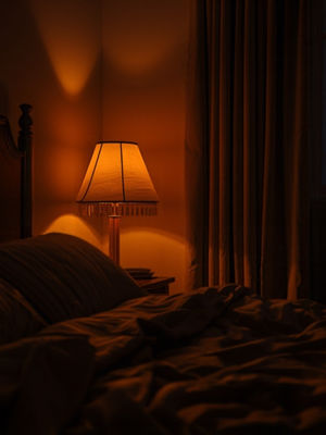 A softly lit bedside table at night with a candle, tea and an open journal, phone face-down