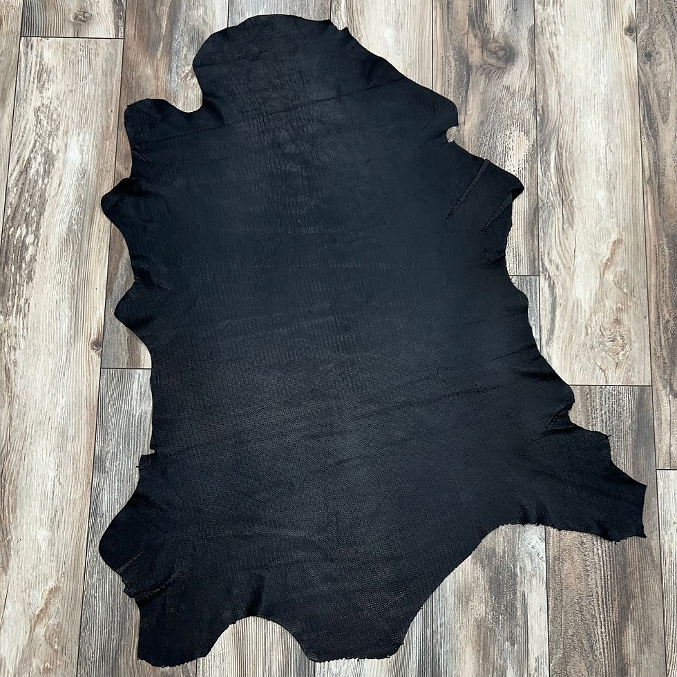 Black half-moon textured Italian leather hide on a wood background