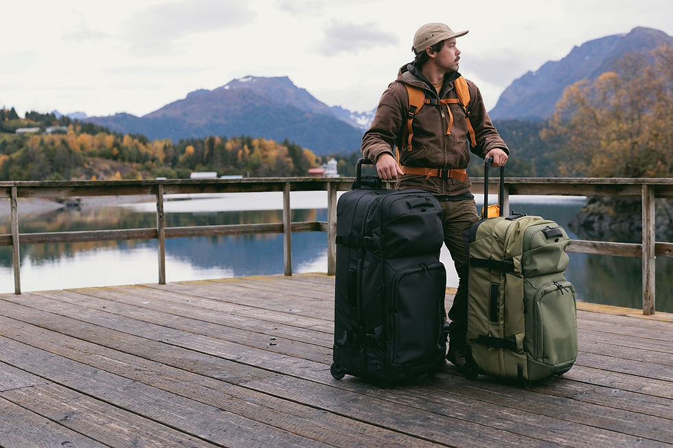 Traveler with Eagle Creek ORV rolling luggage bags on a wooden dock with mountain lake backdrop.