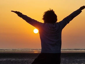 Femme qui ouvre les bras face à un lever de soleil