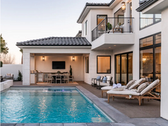 A luxurious backyard with a pool and a covered outdoor kitchen/dining area.