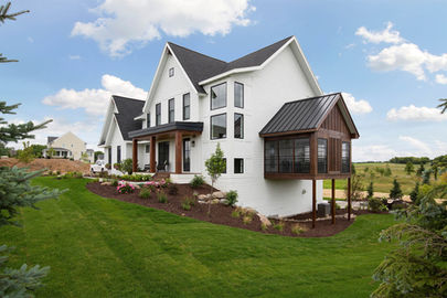 Image of a white house with a black roof on a sunny day. 
