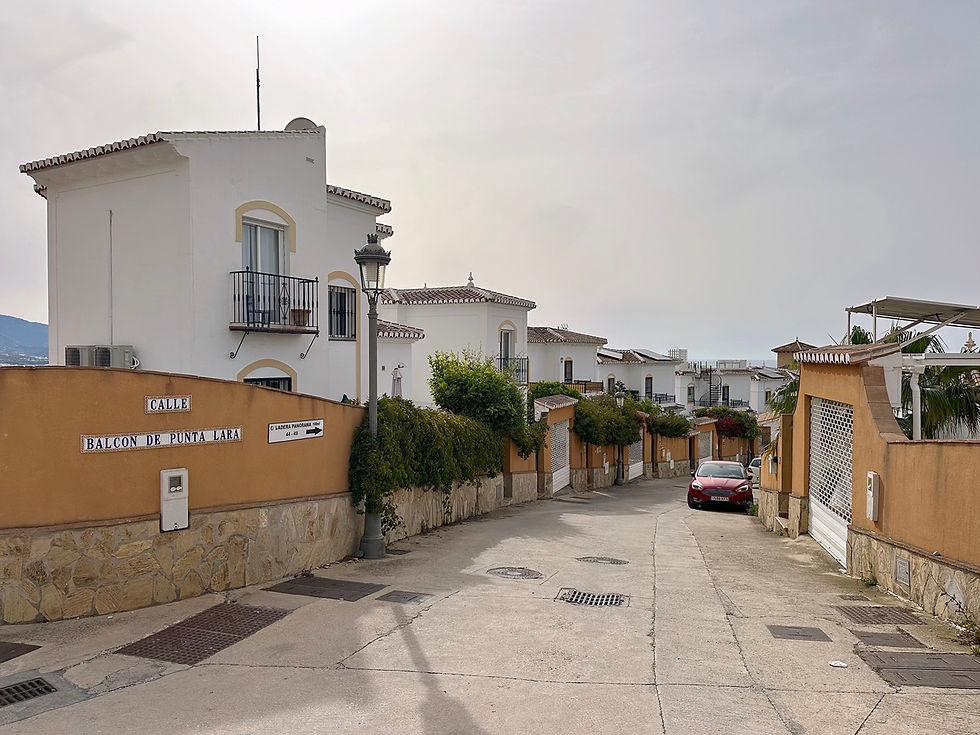 Calle en Punta Lara con casas blancas, coche y cielo azul