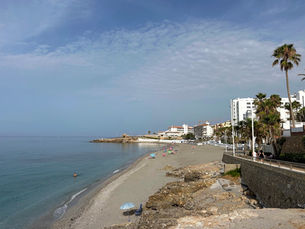 Sandy beach with palm trees and promenade at Playa Torrecilla in Nerja, Spain