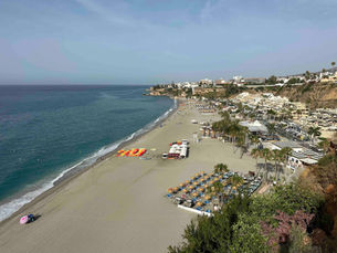 Kesäinen näkymä Burriana-rannasta Nerjassa kuvattuna ylhäältä päin, rannalla riveittäin oransseja kajakkeja ja Välimeri