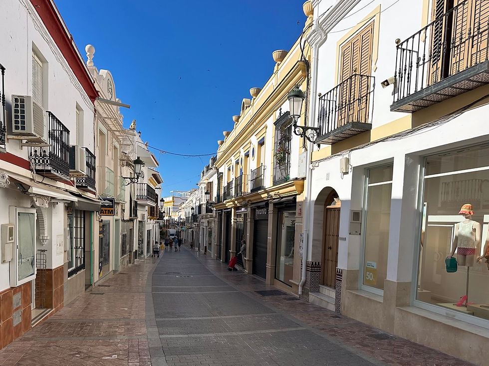 Calle comercial en el casco antiguo de Nerja con tiendas y cielo azul