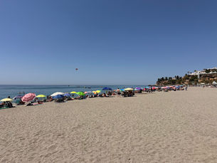 View from Playa Burriana in Nerja with sunbathers and umbrellas