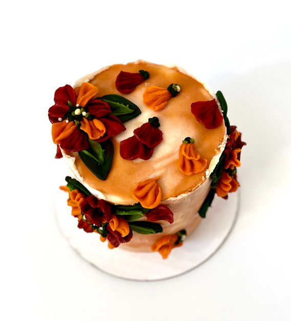 Fall color palette buttercream cake with palette knife leaves and piped flowers and petals.